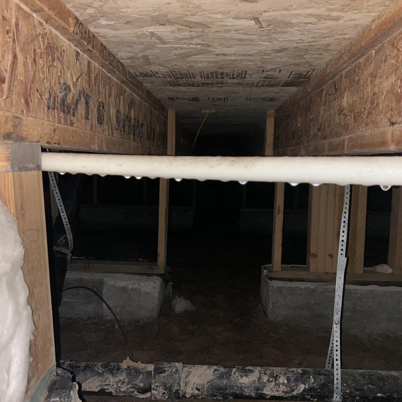 Foundation drainage pipe with water droplets in crawlspace