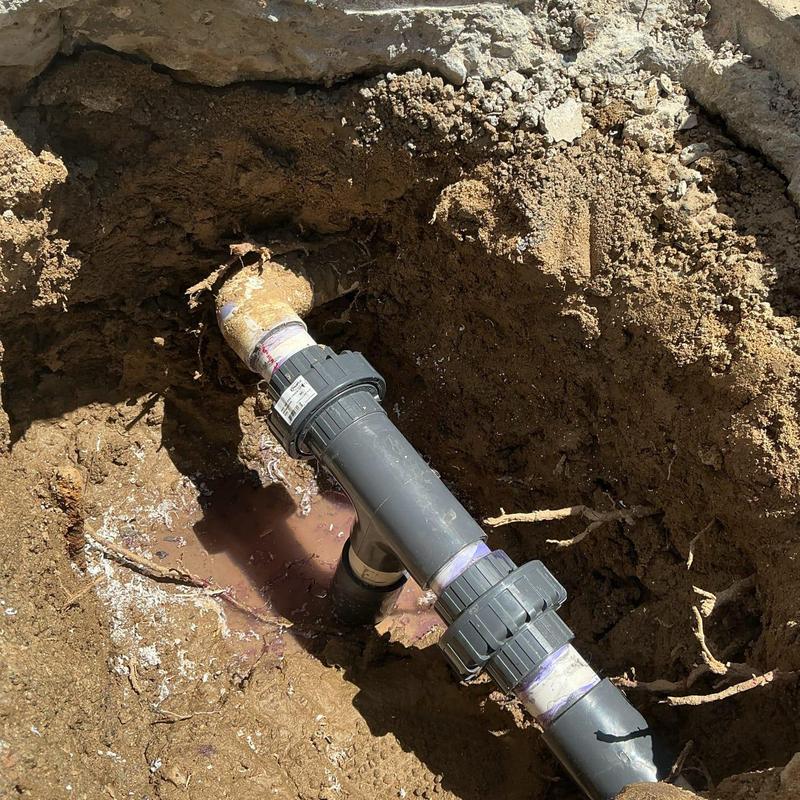 PVC pipe coupling with primer and cement in soil trench