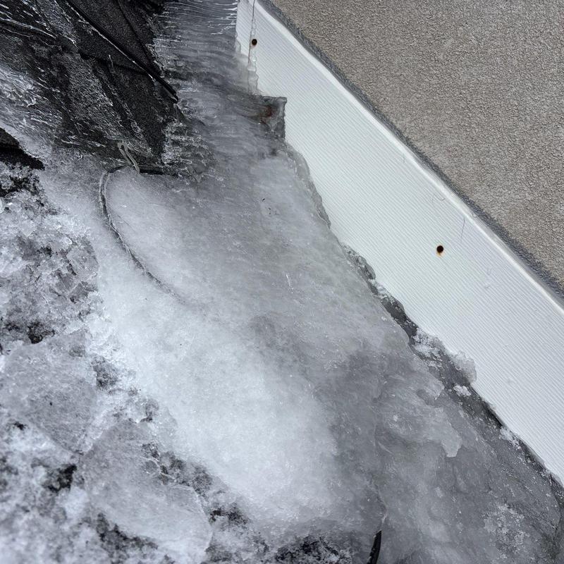 Roof edge ice buildup on shingles near siding trim