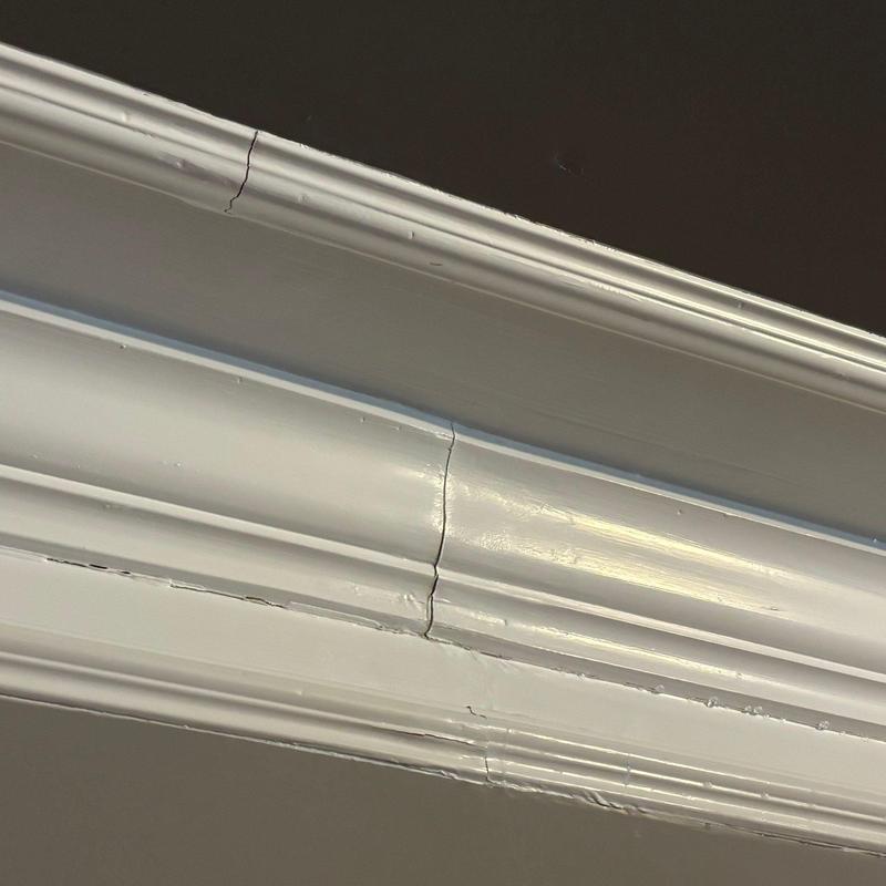 Painted crown molding with visible cracks and damage