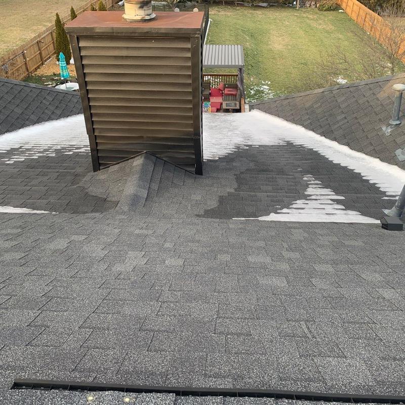 Roof shingles and chimney flashing with snow patches