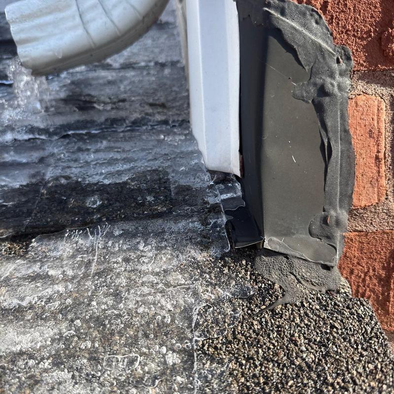 Flat roof edge flashing with sealant by brick wall