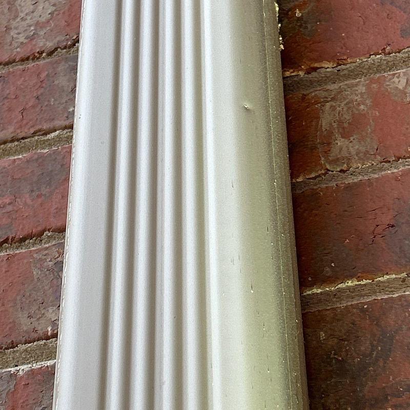 Vinyl downspout with minor dents against brick wall