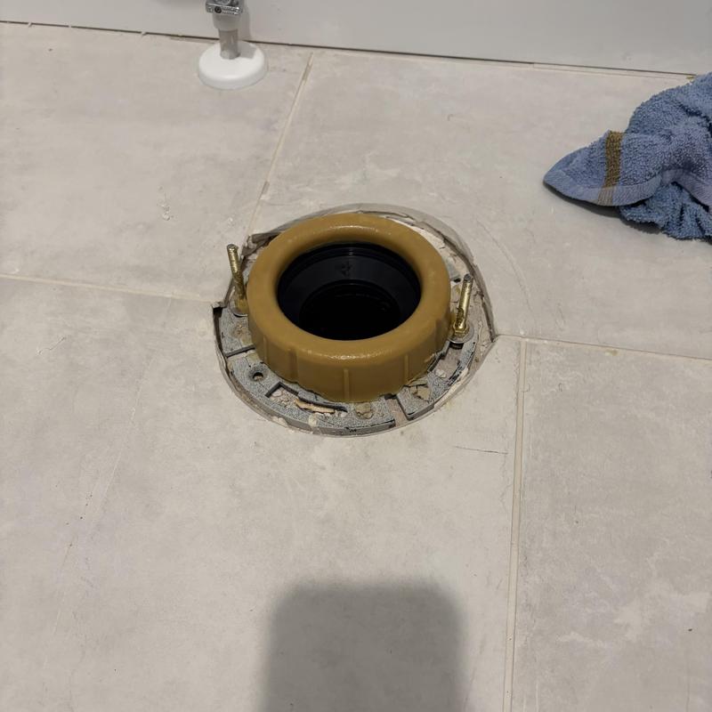 Toilet flange and wax seal on tiled bathroom floor