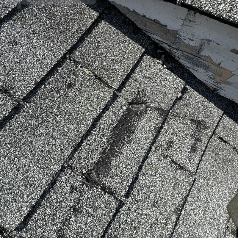 Asphalt roof shingles with wear and damage near flashing