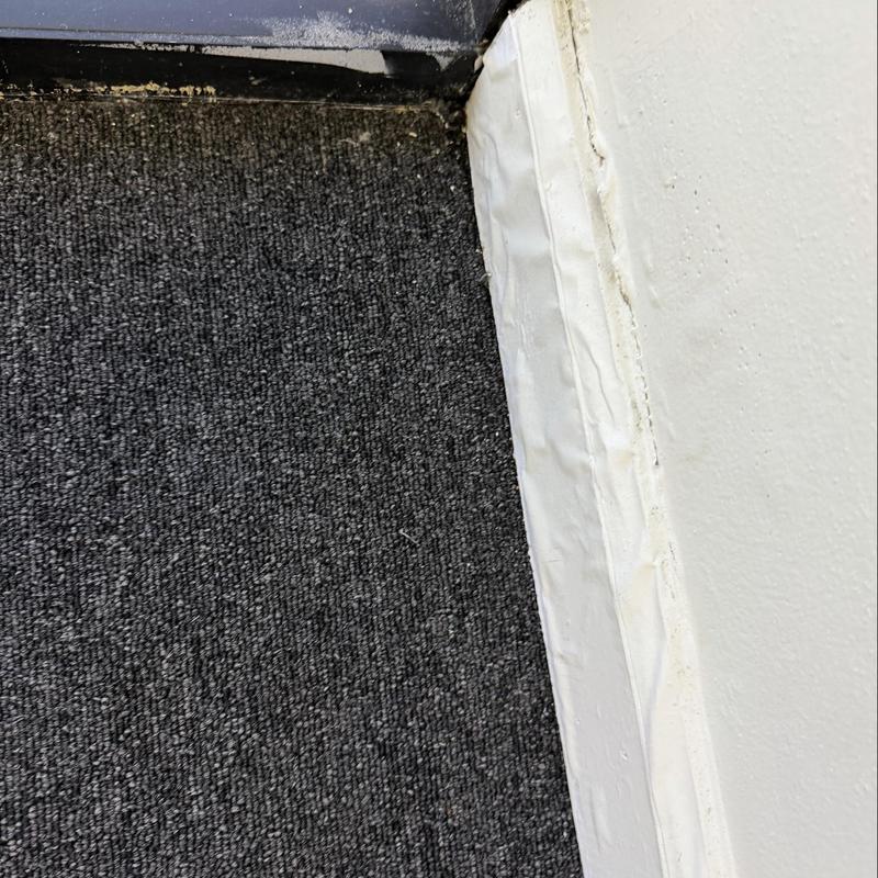 Carpet seam with wrinkled white baseboard trim Carpet seam with wrinkled white baseboard trim