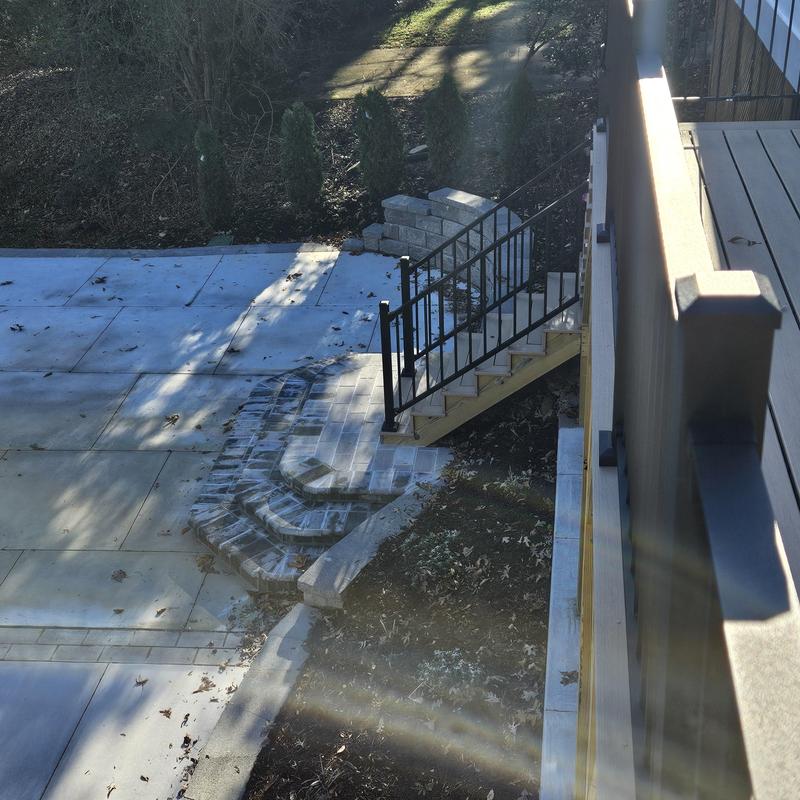 Concrete steps with black metal railing and stone landing Concrete steps with black metal railing and stone landing