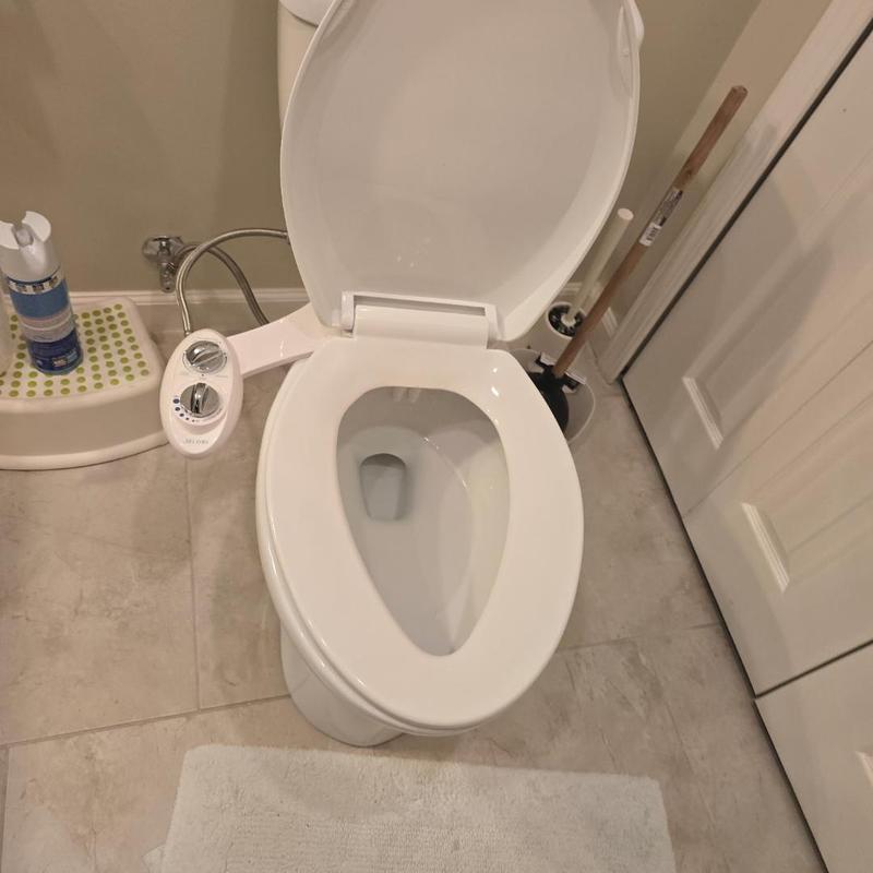 Toilet with bidet attachment and cleaning tools nearby