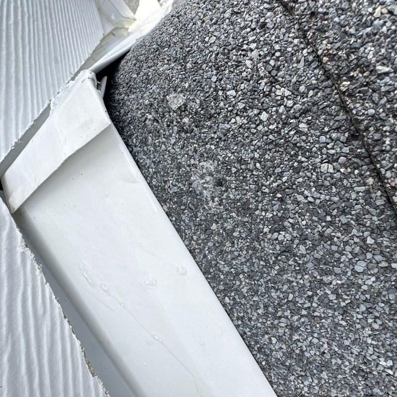 Roof shingles with hail damage near white flashing trim