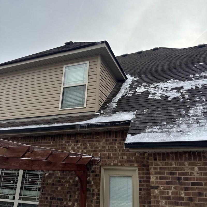 Asphalt roof shingles with ice buildup on slope