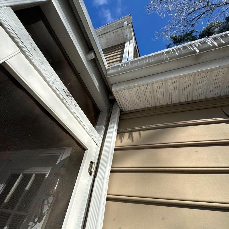 Gutter downspout and siding with icicles on roof edge