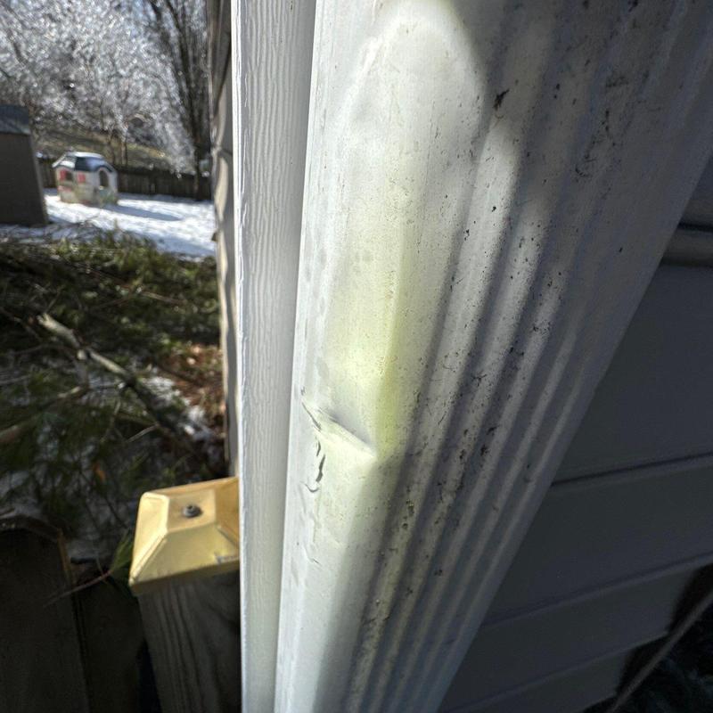 Metal gutter dent with hail damage on house exterior