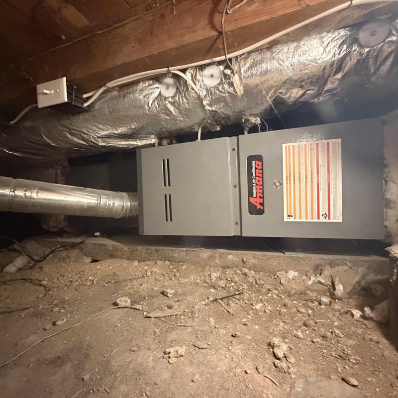 Amana furnace unit in crawlspace with ductwork