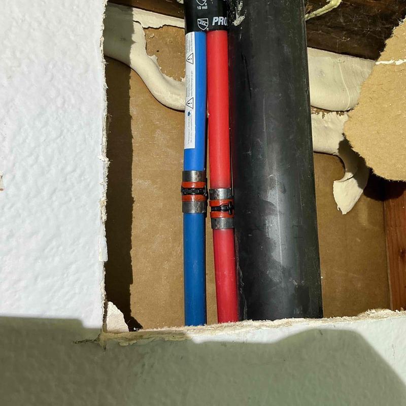 PEX B water pipes with metal clamps inside wall cavity