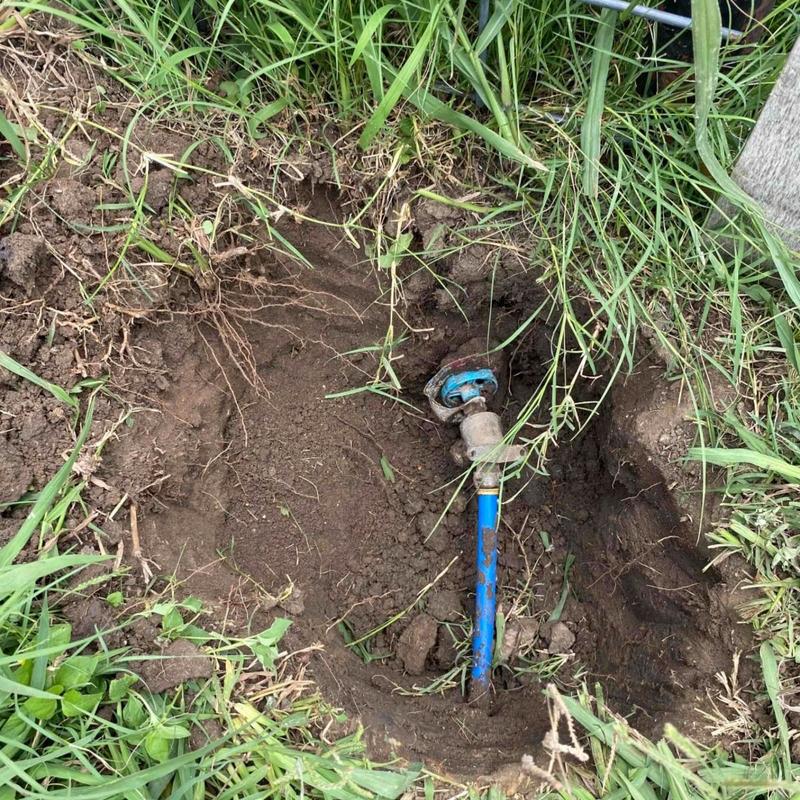 Older hose bib in ground with blue pipe