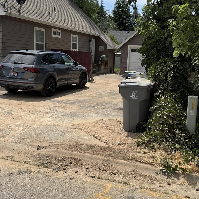 Sewer main repair site with driveway excavation and trash bins