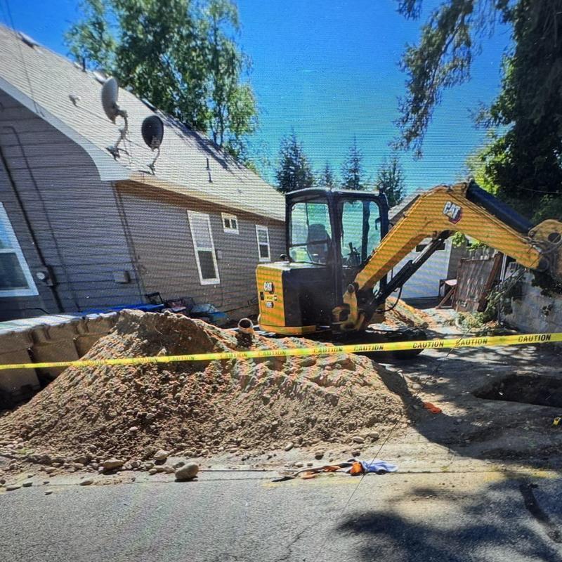 Sewer main excavation with compact excavator and caution tape