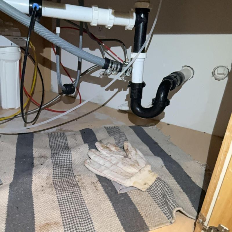 Kitchen sink drain pipe with cleaning gloves on mat