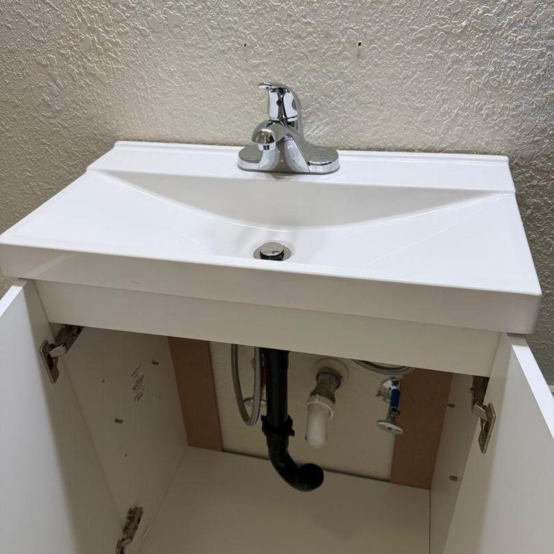 Bathroom sink plumbing and faucet installation with open cabinet Bathroom sink plumbing and faucet installation with open cabinet