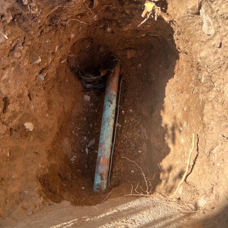 Main waterline excavation and pipe exposure in dirt trench