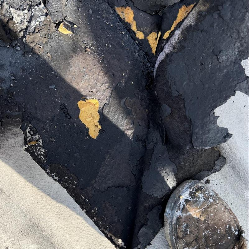 Built-up roofing membrane with damage near boot flashings Built-up roofing membrane with damage near boot flashings