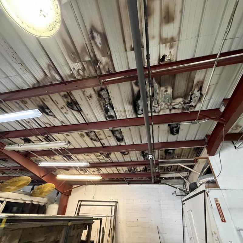 Metal ceiling panels with fire damage in industrial space Metal ceiling panels with fire damage in industrial space