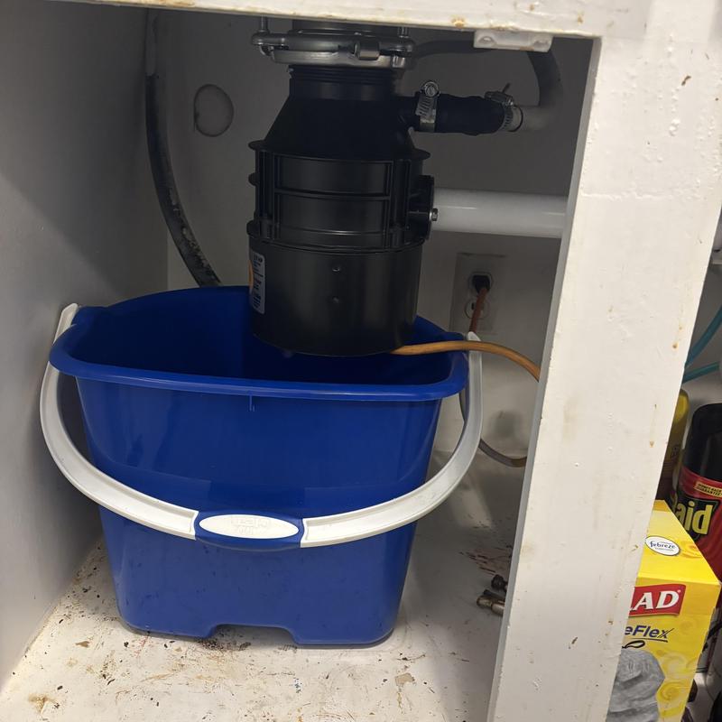 Garbage disposal with blue catch bucket under sink