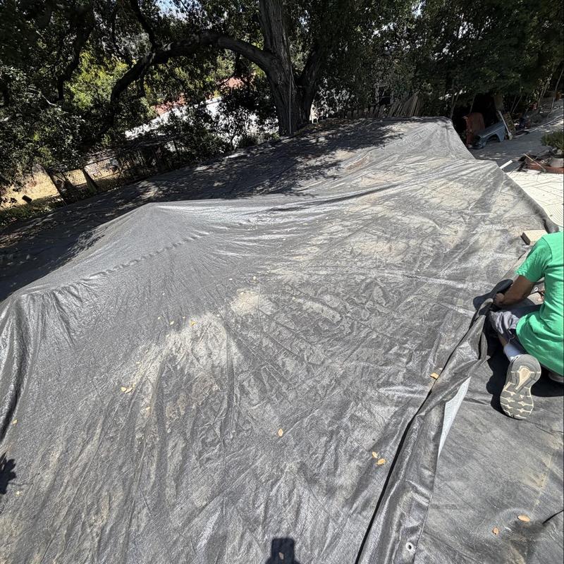 Flat roof protective tarp installation with technician nearby Flat roof protective tarp installation with technician nearby