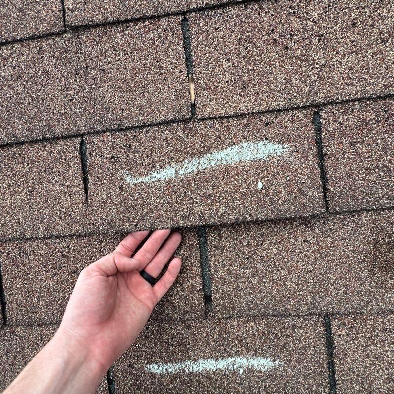 Asphalt roof shingle with hail damage marked for repair
