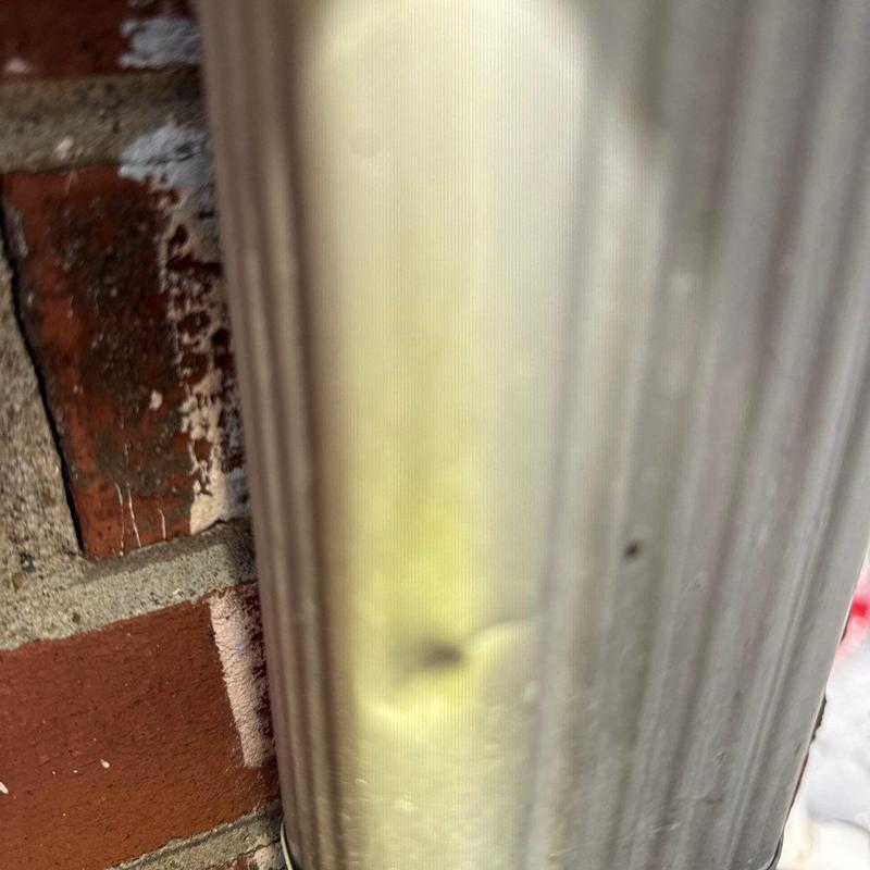 Downspout dent from hail impact on gutter system