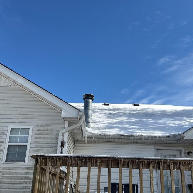 Roof shingles with snow and icicle buildup on gutter edge