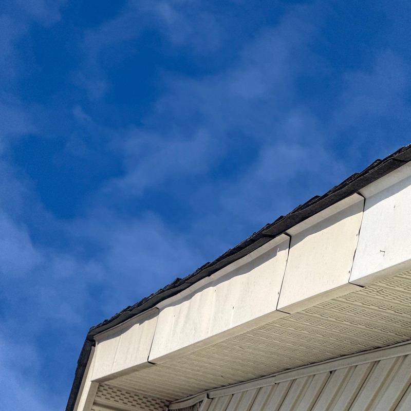 Roof edge panels showing hail damage under blue sky