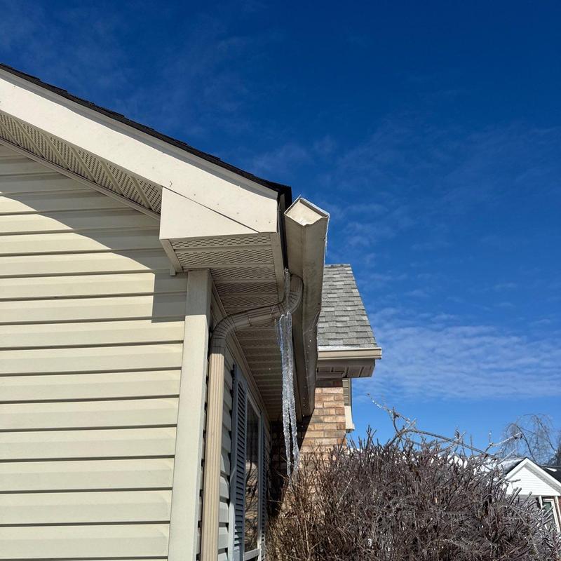 Gutter system with icicle formation on house exterior