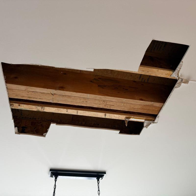 Ceiling drywall with large cutout exposing wood joists