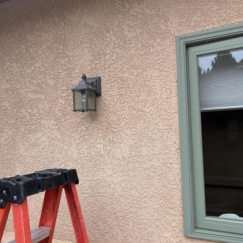 Exterior wall light fixture and window trim near ladder