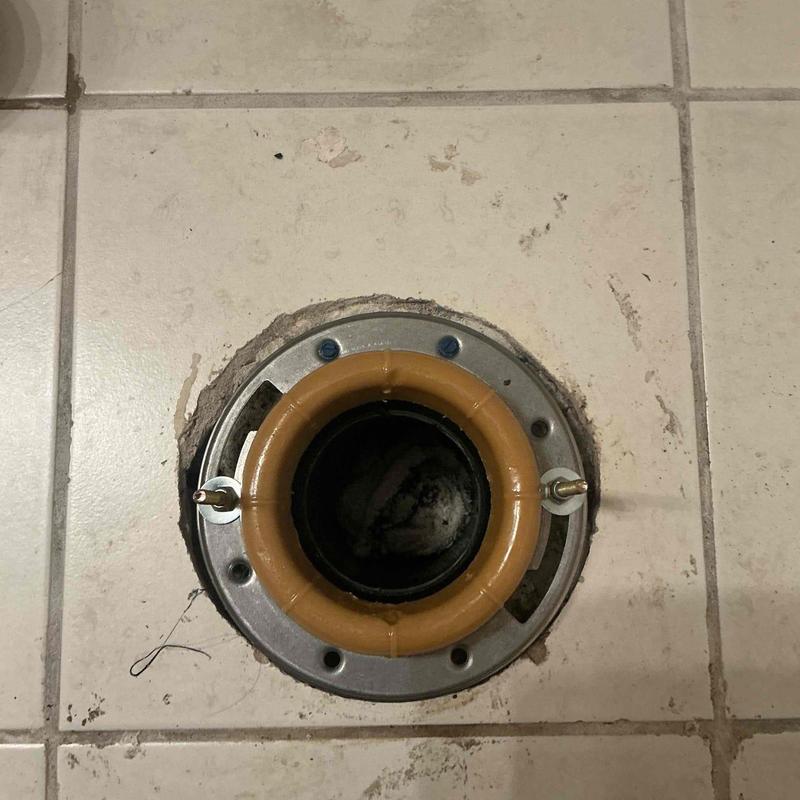 Toilet flange with new wax ring installed on tiled floor