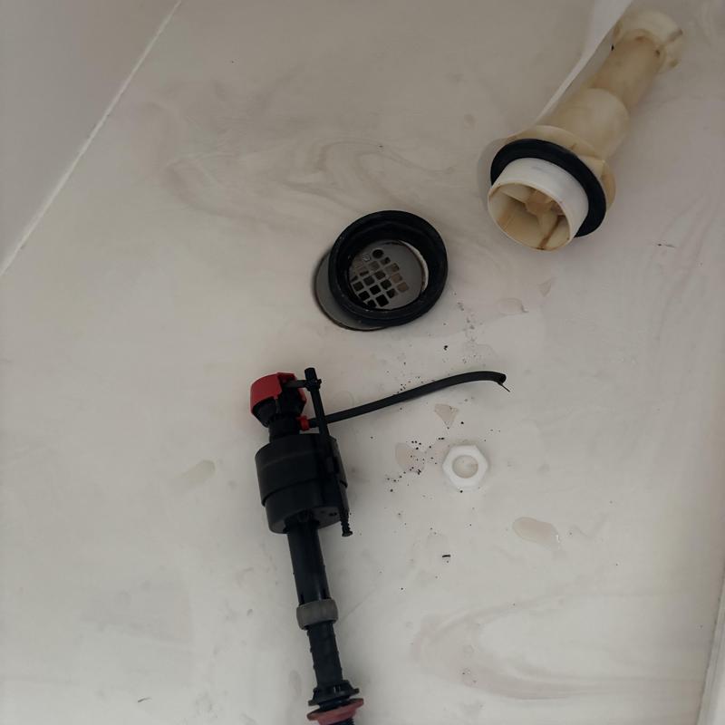 Toilet fill valve and flush valve parts on tub floor