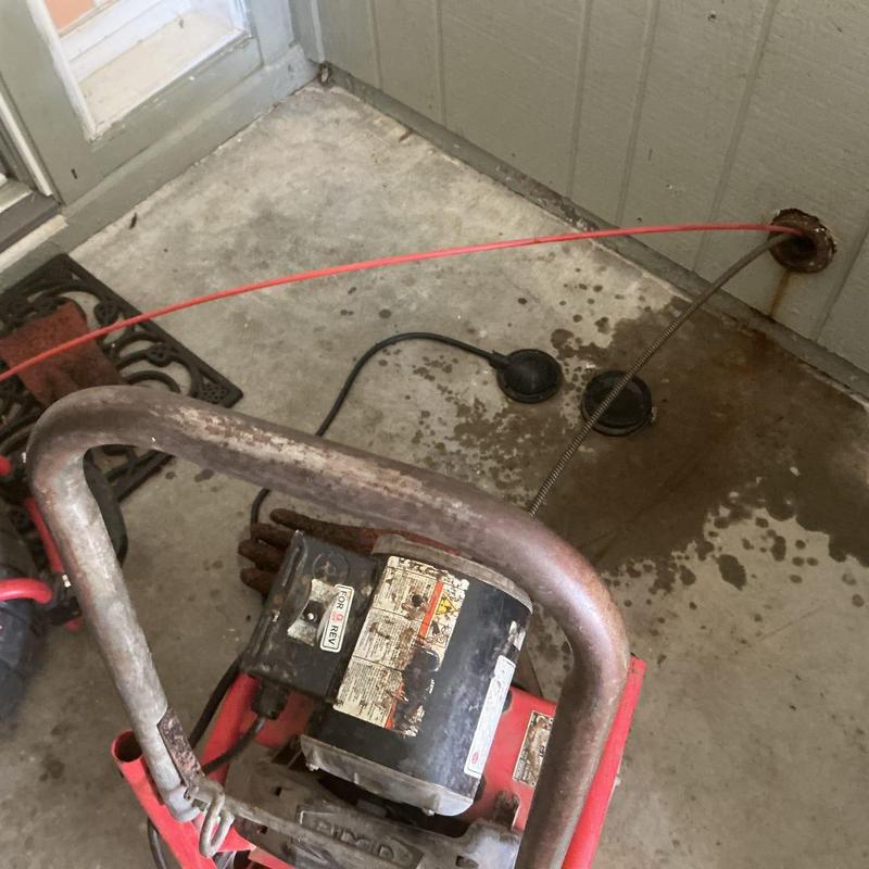 Drain cleanout with plumbing snake clearing blockage