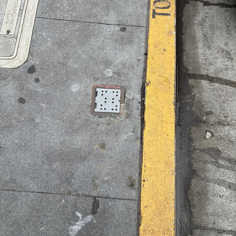Sewer cleanout cover on sidewalk near curb and street