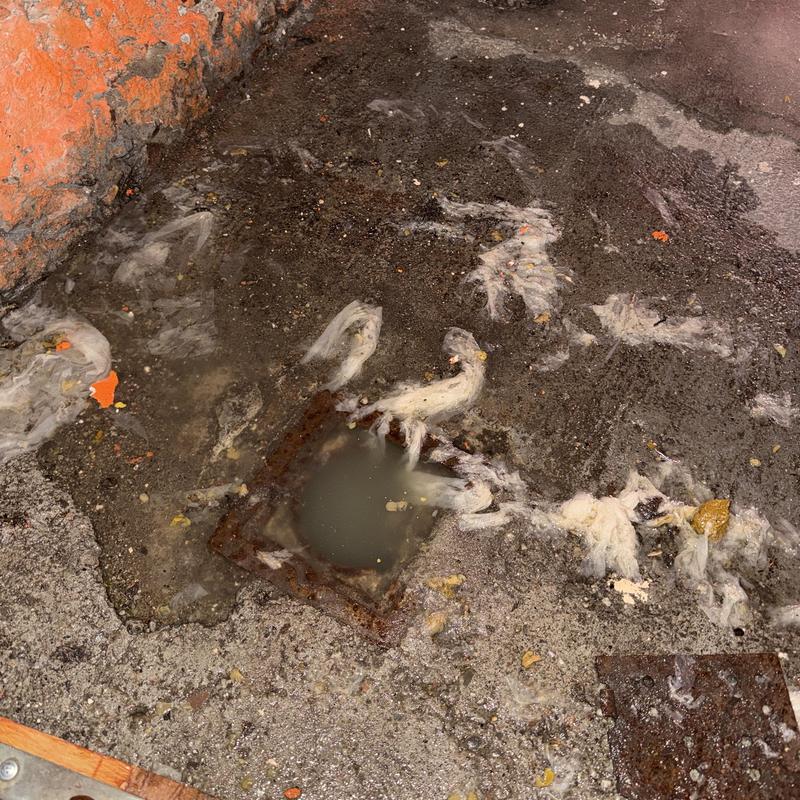 Sewer drain with clogged dirty water and debris outdoors