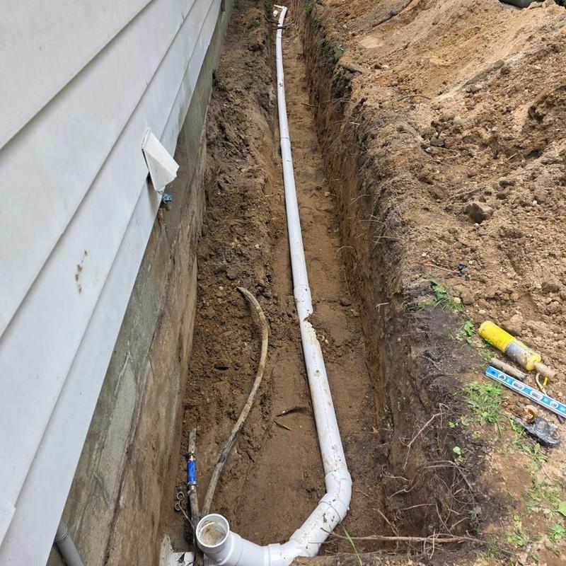 Sewer line relocation trench beside house foundation