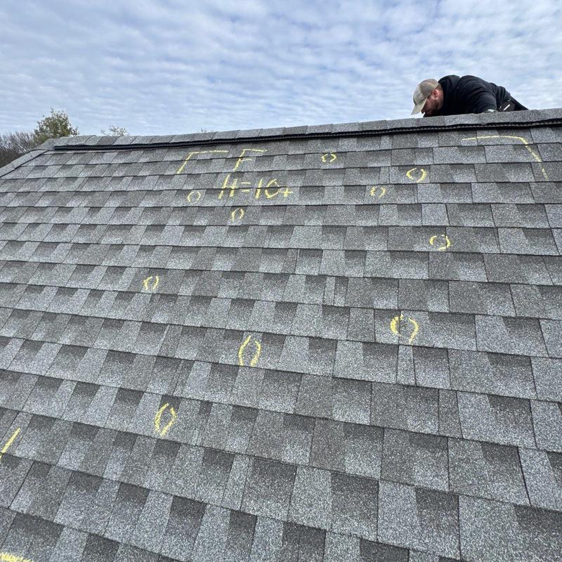 Shingle roof with hail damage markings and inspector