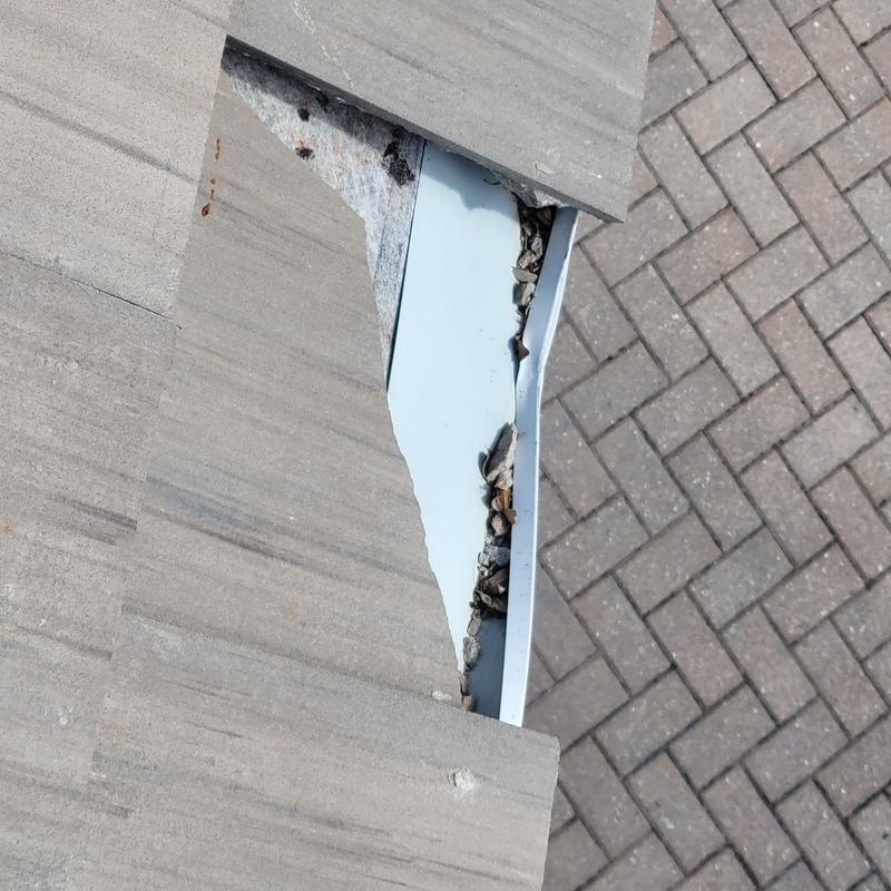 Concrete tile roof with exposed metal flashing and debris
