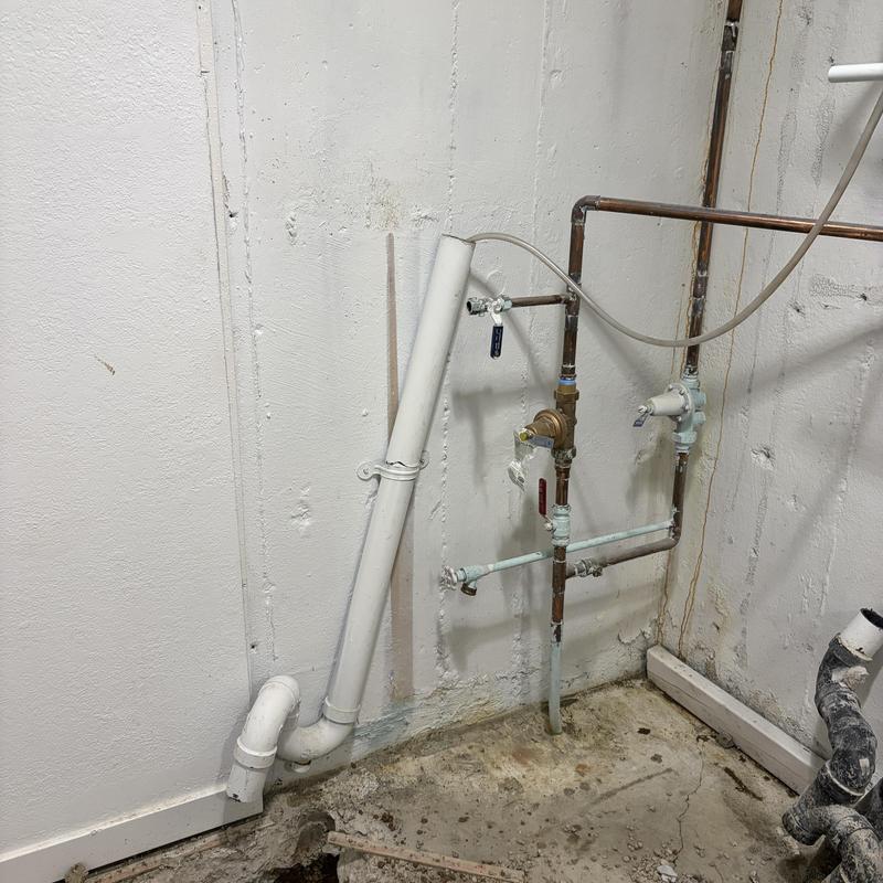PVC drain pipe replacement in basement corner