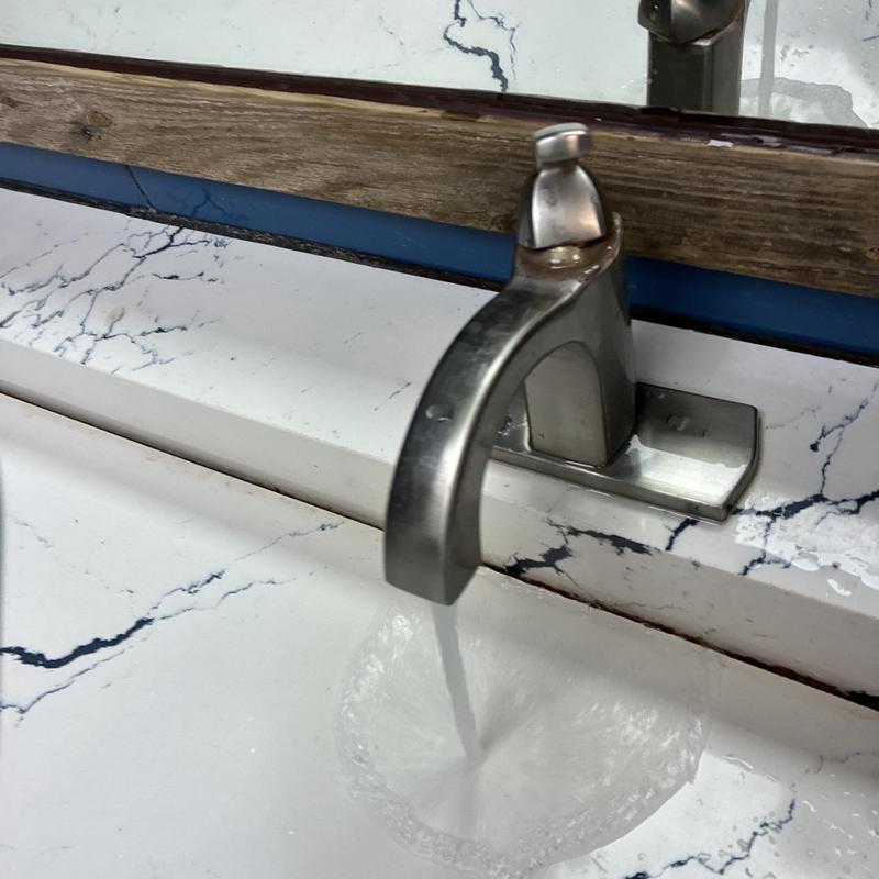 Bathroom sink faucet with running water and wooden mirror trim Bathroom sink faucet with running water and wooden mirror trim