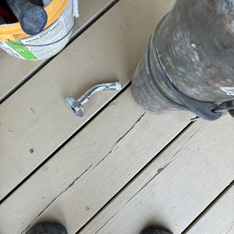 Broken chrome shower arm on wooden deck floor Broken chrome shower arm on wooden deck floor