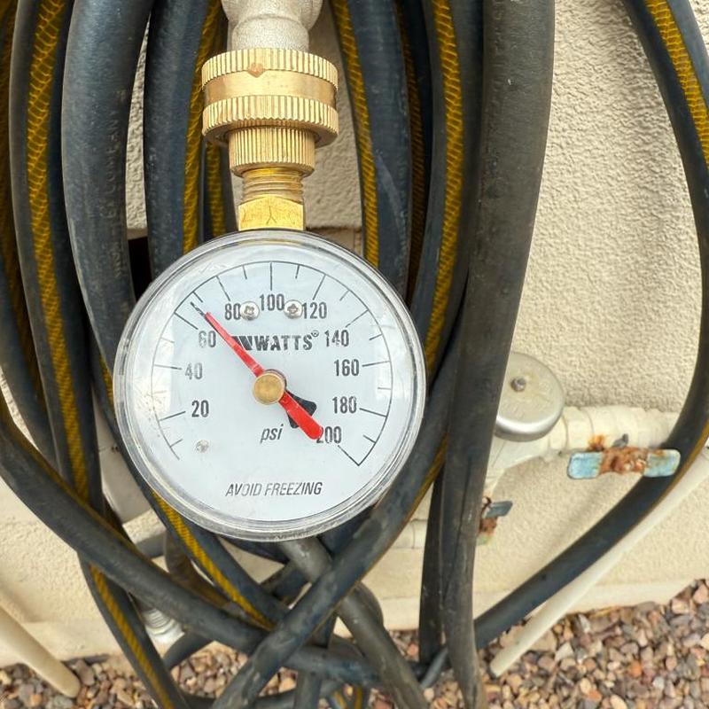 Pressure gauge on water supply pipe with hose coils