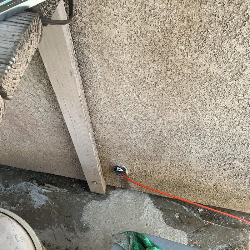 Orange outdoor electrical extension cord plugged into wall outlet