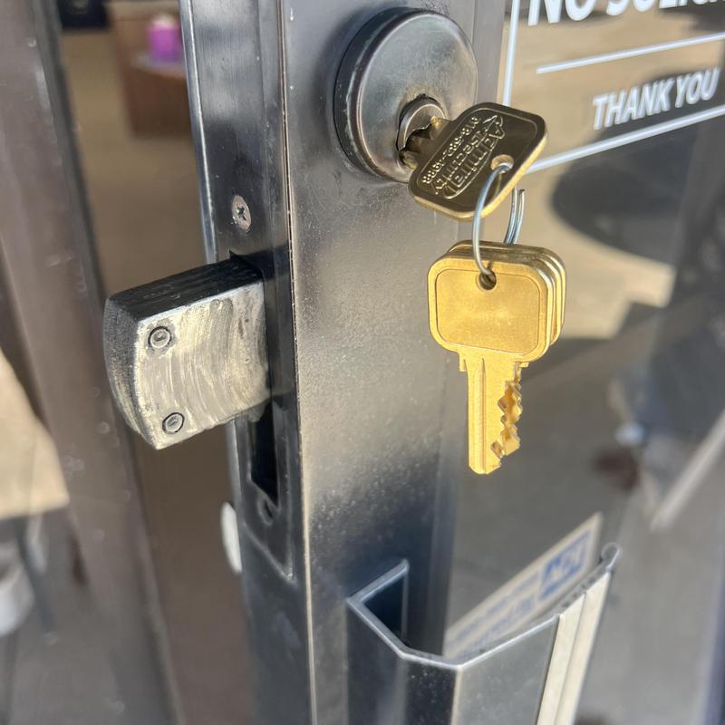 Commercial keyed deadbolt lock on metal door with keys