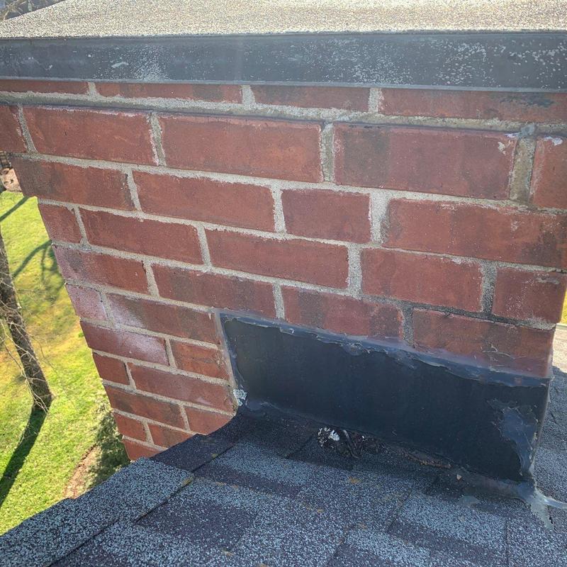 Chimney flashing on shingle roof with wear and cracks